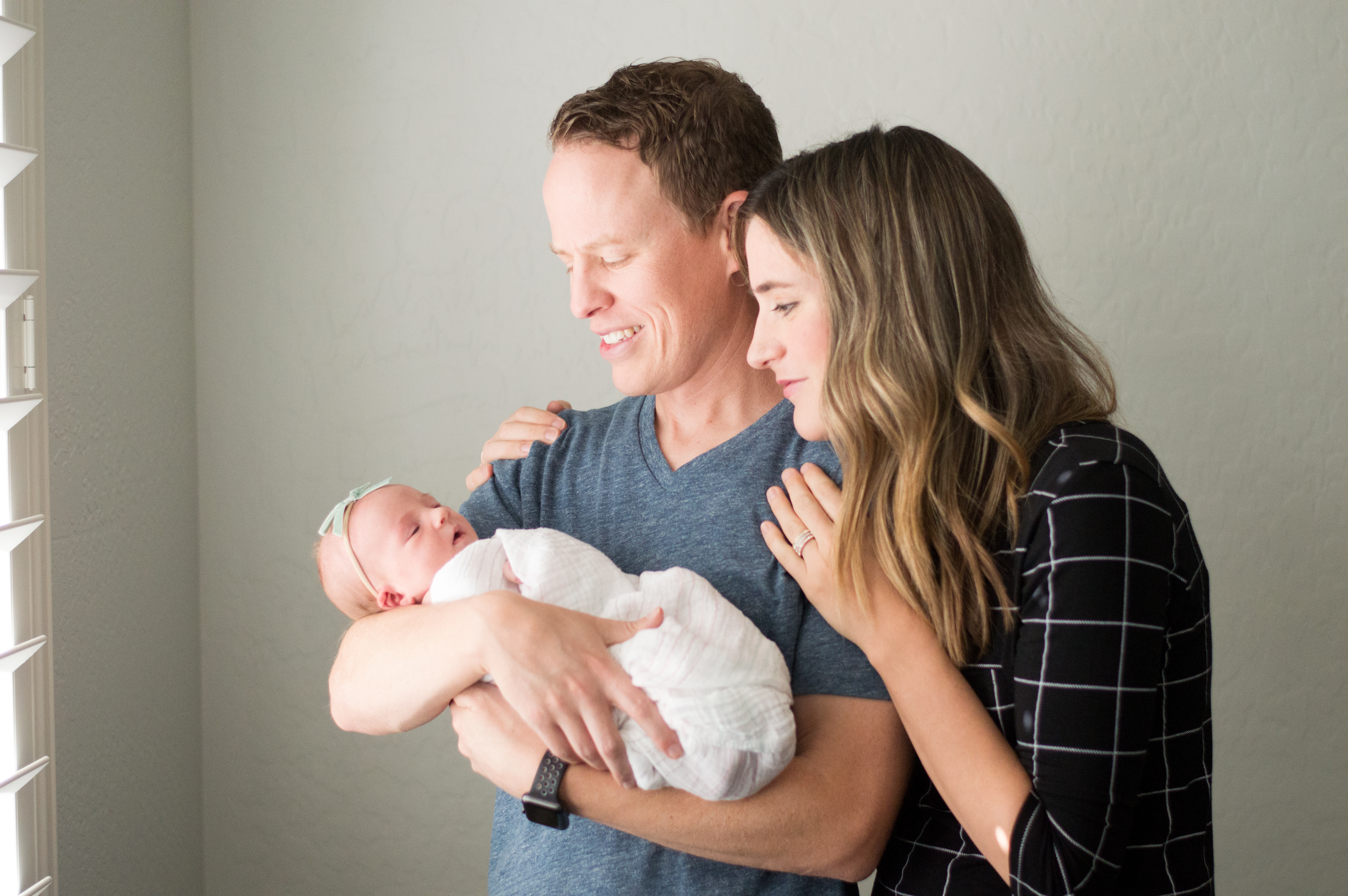 Parents with baby girl photographed during in home lifestyle newborn portrait session.