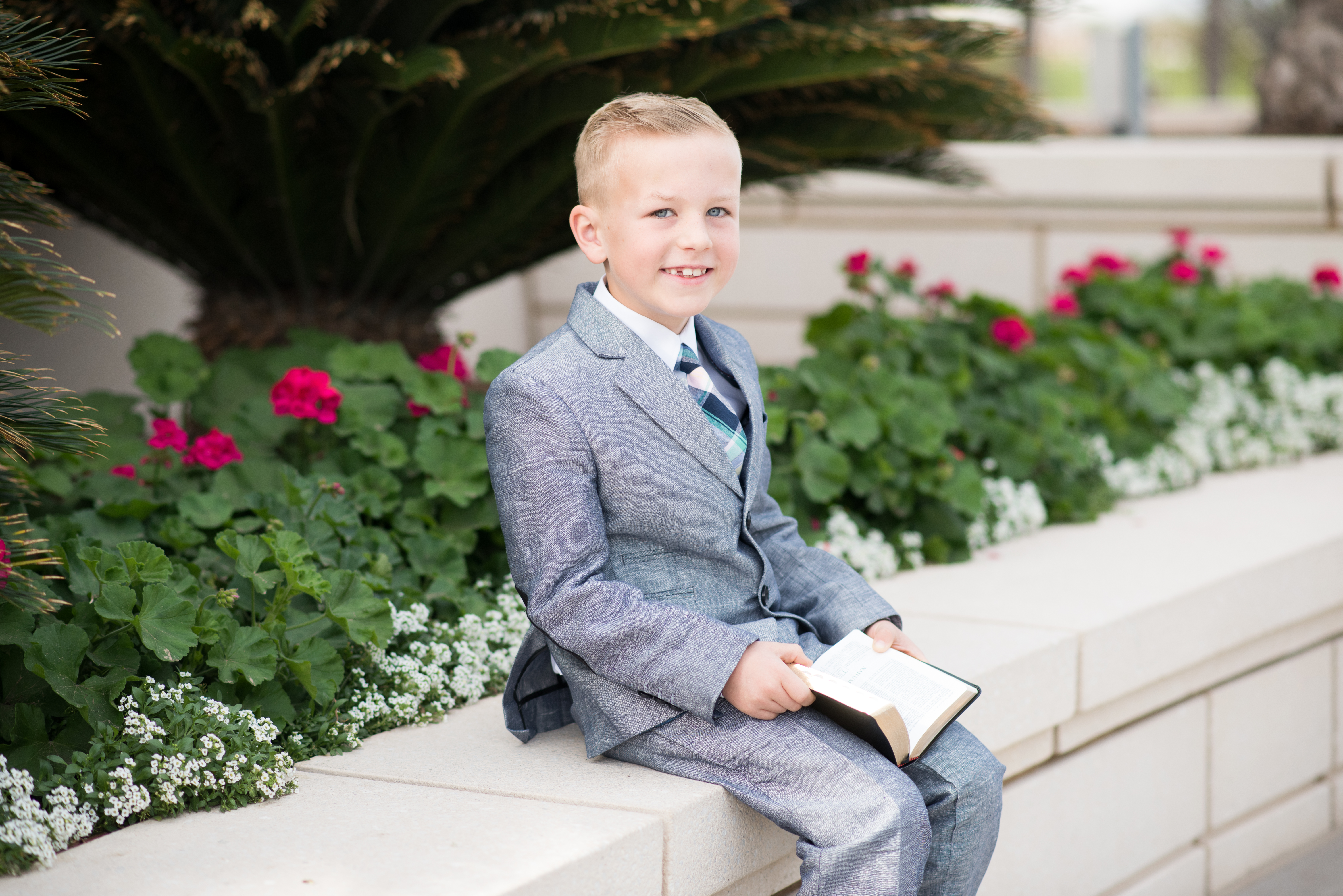 Eight year old boy in suit with scriptures for baptism portraits at the Gilbert LDS Temple. Arizona photographer Melissa Maxwell of Jubilee Family Photography.