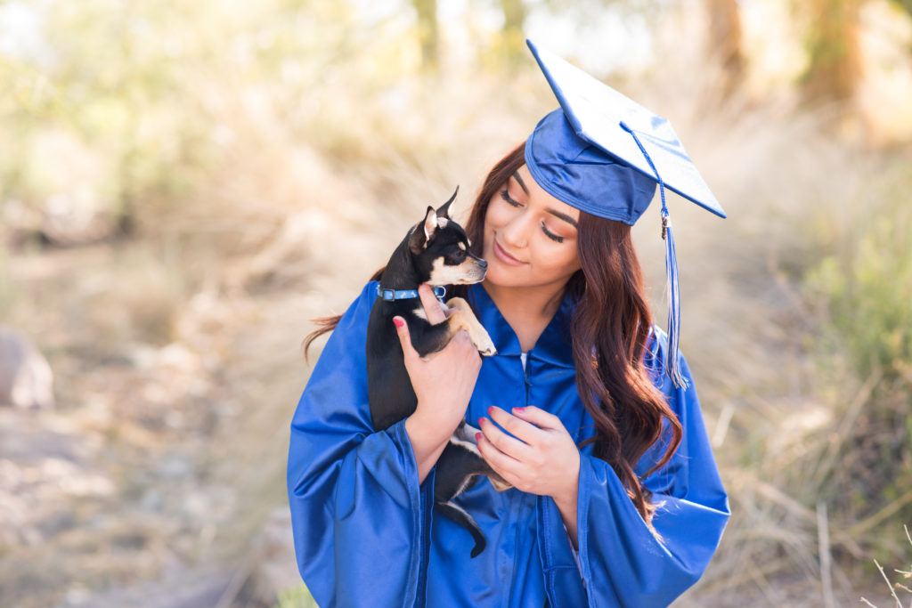 Graduating senior girl in blue cap and gown with dog photographed at the Riparian Preserve in Gilbert, Arizona by Melissa Maxwell of Jubilee Family Photography.